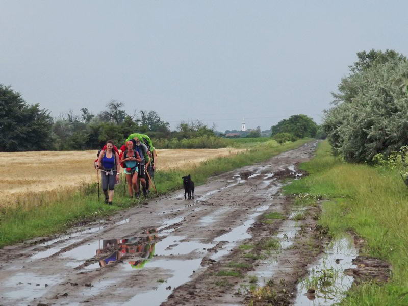 Túrázók jönnek szembe velem a sáros út túlsó oldalán