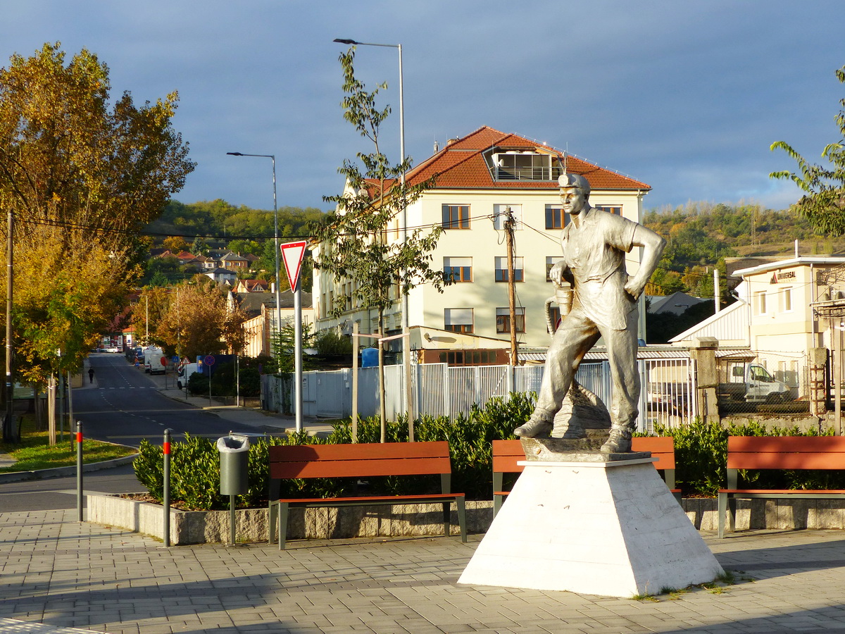 A bányászszobor mögött a dorogi Bányaigazgatóság és a Bányafürdő épülete áll