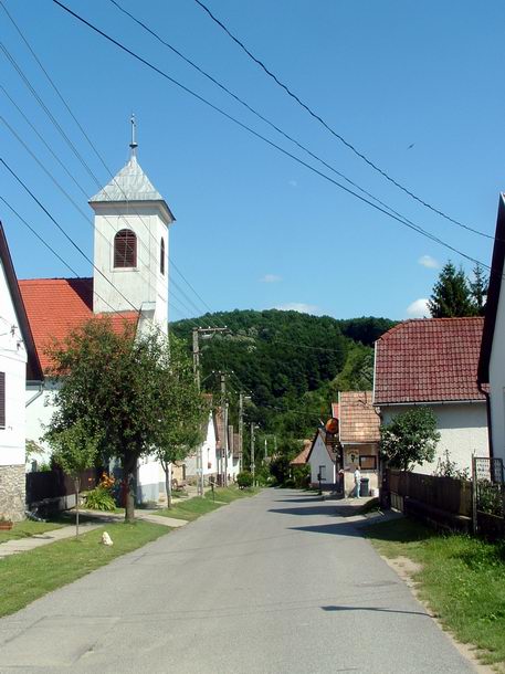 Óbánya - A falu főutcáján balra áll a templom, vele szemben a jobb oldalon pedig a pecsételő helyként szolgáló kis kocsma látható