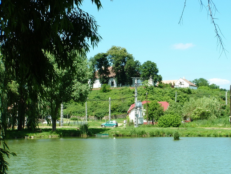 Cserhátsurány - A kis horgásztó mögött feltűnik a Jánossy kastély