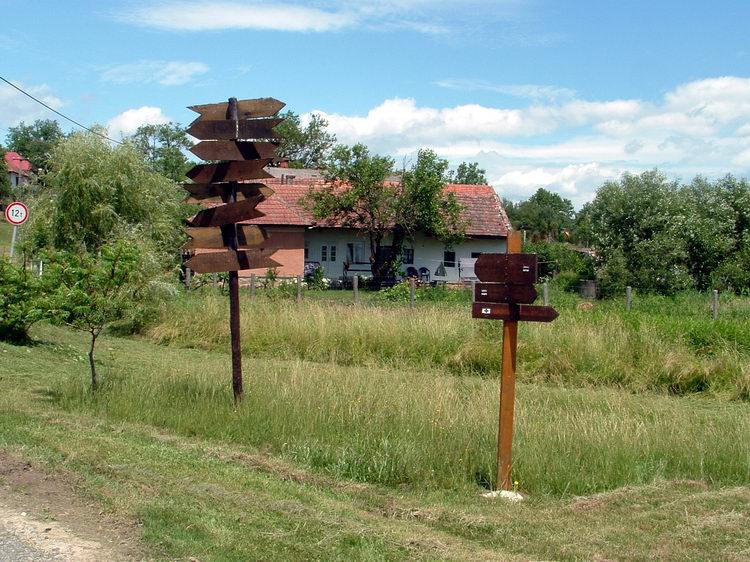 Tornabarakony - Útjelző táblák a templom előtt. A nagyobbik oszlopon az európai nagyvárosok távolsága van jelölve.